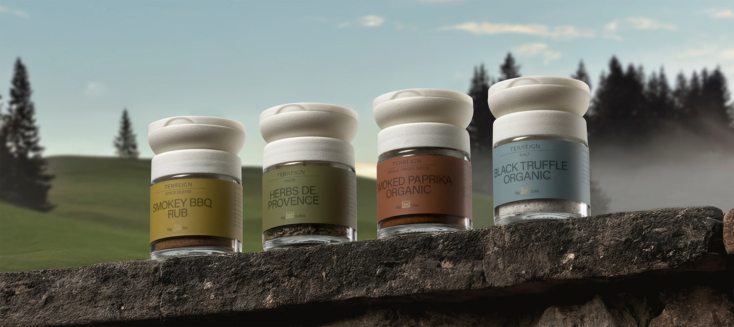 Four small jars of spices on a stone ledge with a scenic background